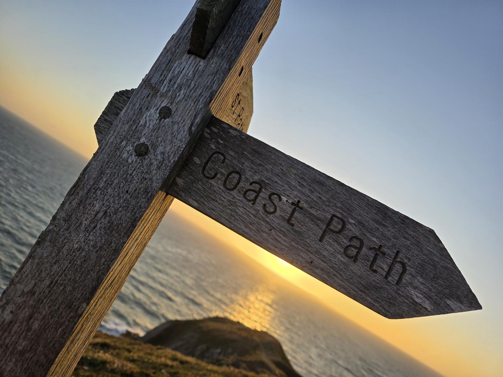 Coast Path signpost at Baggy Point at sunset